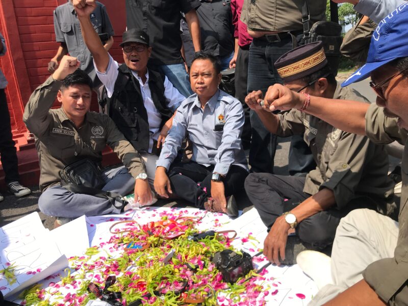 Insan media Nganjuk sedang melakukan aksi tabur bunga di atas kartu pers mereka di pintu gerbang gedung DPRD Nganjuk.(Poto:ifakta.co /may)