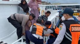 Momen Briptu M. Ilham membantu seorang Lansia yang kesulitan turun dari kapal di Dermaga Kali Adem, Pelabuhan Muara Angke, Kamis (26/12/2024). 